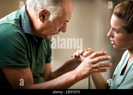 Senior uomo ricevere cattive notizie da parte di un infermiere. Foto Stock