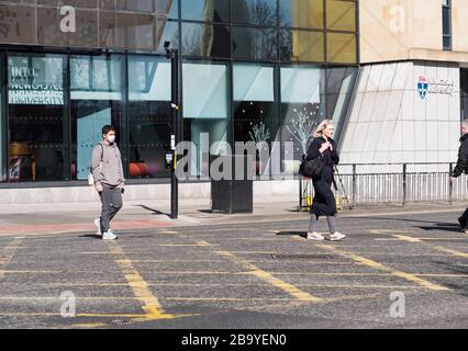 Newcastle upon Tyne, Regno Unito, 19 marzo 2020. Una croci asiatiche dell'Università di Newcastle indossando una maschera come protezione contro il corvid-19, il coronavirus Foto Stock