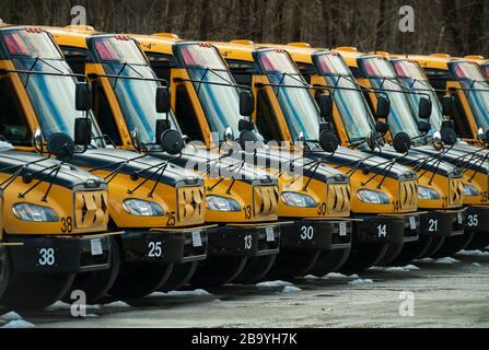 Lexington, Massachusetts, Stati Uniti. 24 marzo 2020. Più di 50 scuolabus inattivi nel pomeriggio di un giorno feriale. Lexington, con una popolazione di oltre 30,000 abitanti, vicino a Boston, Massachusetts, ha chiuso le 11 scuole pubbliche della città a causa del fatto che il Coronavirus ha colpito i 7,000 studenti del distretto scolastico. Credit: Chuck Nacke / Alamy Live News Foto Stock