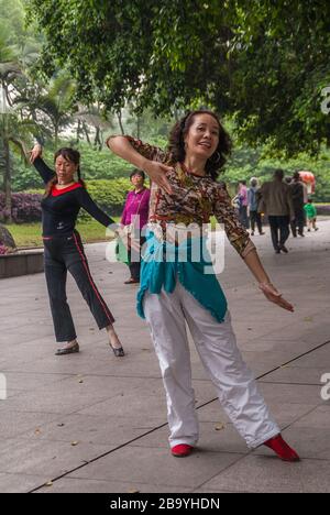 Chongqing, Cina - 9 maggio 2010: Spettacolo di danza di gruppo nel parco dello zoo. Primo piano di 2 donne in movimento sincronizzato sulla musica. Altre persone e gr Foto Stock