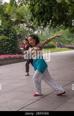 Chongqing, Cina - 9 maggio 2010: Spettacolo di danza di gruppo nel parco dello zoo. Primo piano di 2 donne in movimento sincronizzato sulla musica. Fogliame verde. Foto Stock