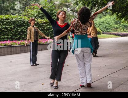 Chongqing, Cina - 9 maggio 2010: Spettacolo di danza di gruppo nel parco dello zoo. 2 donne che si muovono insieme e si sincronizzano sulle melodie della musica. Altri ballerini pre Foto Stock