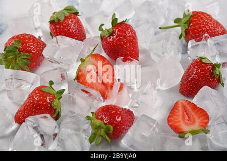 Primo piano su fragole fresche rosse mature e cubetti di ghiaccio sul tavolo, vista ad angolo alto Foto Stock