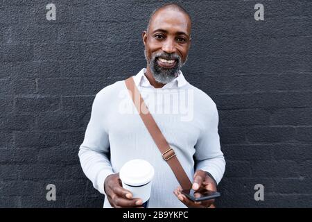 Uomo africano americano che usa il suo telefono per strada Foto Stock