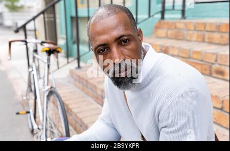 Uomo afro-americano seduto su scale guardando la macchina fotografica
