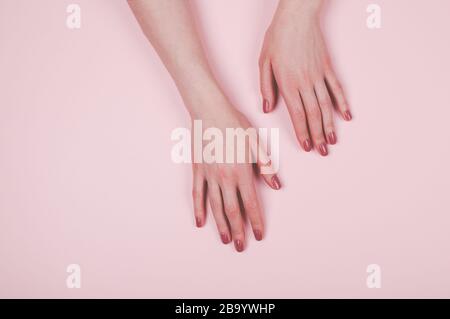 Donna mani con manicure su sfondo rosa chiaro Foto Stock