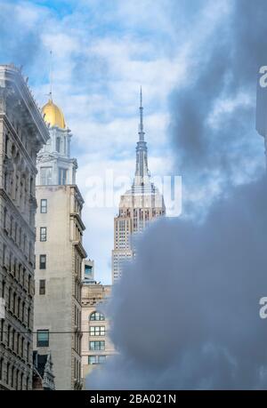 Il vapore sale e si sposta tra gli edifici Midtown Manhattan di fronte all'Empire state Building a New York City NY USA il 2018 dicembre. Foto Stock