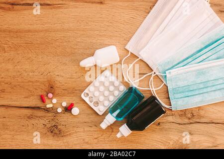 Vista dall'alto di diverse pillole, compresse, farmaci, medicamenti, sanitizzanti, gocce nasali e maschere protettive mediche su tavolo di legno. Trattamento e preventio Foto Stock