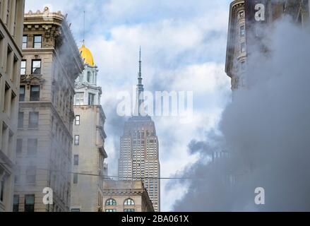 Il vapore sale e si sposta tra gli edifici Midtown Manhattan di fronte all'Empire state Building a New York City NY USA il 2018 dicembre. Foto Stock