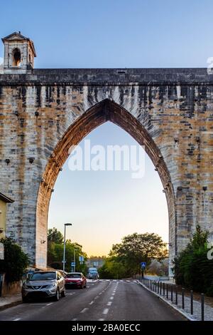 Automobili parcheggiate sulla Rua 12, che attraversa un arco di Águas Livres Aqueduct a Lisbona. Foto Stock