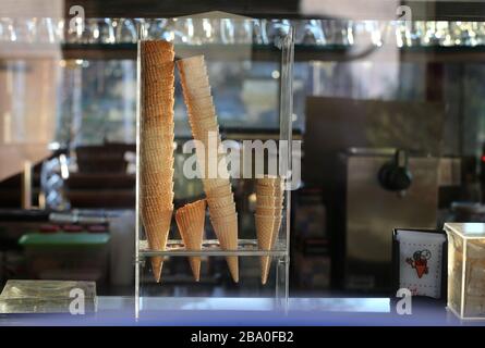 Immenstadt, Germania. 25 Marzo 2020. Sundaes e cialde di ghiaccio sono impilati dietro il vetro della finestra di un gelateria chiuso sul lungomare del grande Alpsee. Credit: Karl-Josef Hildenbrand/dpa/Alamy Live News Foto Stock