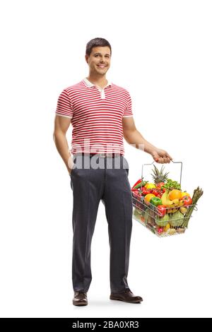 Ritratto a tutta lunghezza di un giovane uomo sorridente e in possesso di un cestino con frutta e verdura sana isolato su sfondo bianco Foto Stock