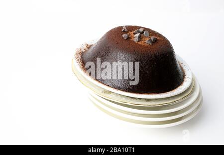 Budino di cioccolato fatto in casa cosparso di polvere di cacao e decorato con gocce di cioccolato, isolato su sfondo bianco. Concetto di dessert. Spazio di copia Foto Stock