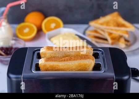 Fette di ottimo pane tostato uscenti dal tostapane. Cucina sana per la colazione e tecnologia di riscaldamento. Mettere a fuoco su fetta di grande. Foto Stock