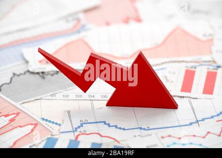 Concetto di crisi finanziaria con freccia rossa in calo sulle carte finanziarie dai giornali Foto Stock