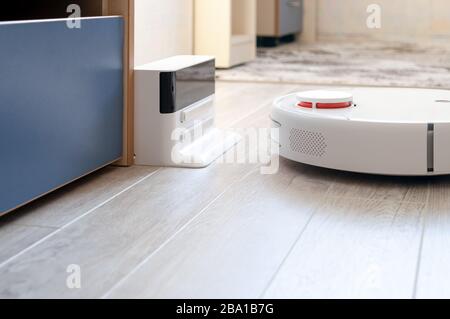 Aspirapolvere roboticobotico rotondo bianco su laminato - tecnologia per la casa Foto Stock