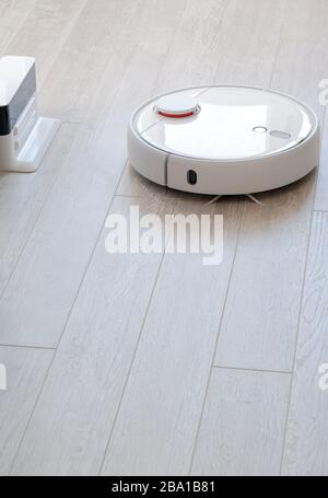 Aspirapolvere roboticobotico rotondo bianco su laminato - tecnologia per la casa Foto Stock