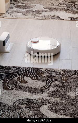 Aspirapolvere roboticobotico rotondo bianco su laminato - tecnologia per la casa Foto Stock