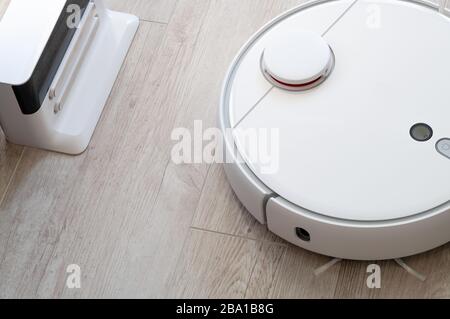 Aspirapolvere roboticobotico rotondo bianco su laminato - tecnologia per la casa Foto Stock