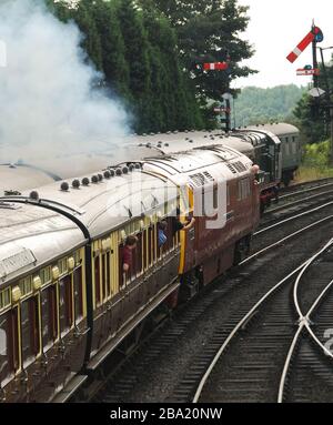 Bridgenarth, Inghilterra - Agosto 2016: Un treno trainato da una locomotiva diesel di Classe Occidentale che passa un portale di segnale sulla Severn Valley Railway Foto Stock