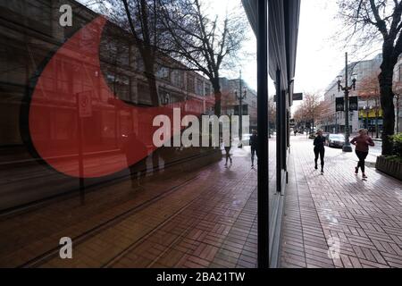 Portland, Stati Uniti. 25 Marzo 2020. Le donne corrono oltre il negozio Nike chiuso a Portland, Ore., il 25 marzo 2020. I centri commerciali sono uno dei molti affari costretti a chiudere sotto l'ordine esecutivo del Governatore Brown che chiede alle persone di rimanere a casa tranne per i bisogni essenziali, come più estreme misure di distanza sociale mirano a rallentare la diffusione del romanzo coronavirus (COVID-19) e appiattire la curva. (Foto di Alex Milan Tracy/Sipa USA) Credit: Sipa USA/Alamy Live News Foto Stock