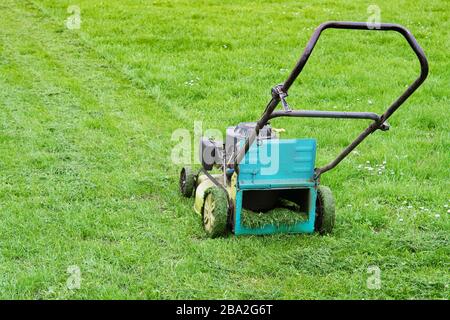 Tosaerba in giardino a lavorare in erba alta Foto Stock