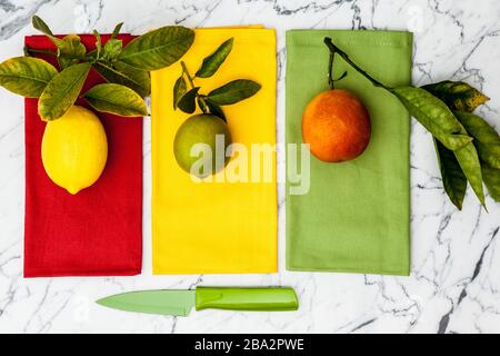 limone, lime e sangue arancio con coltello da parare su bancone in marmo Foto Stock