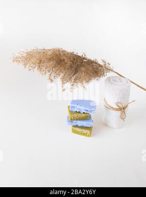 Saponette di lavanda e olive fatte in casa, asciugamano whitel e un pettine secco su sfondo bianco. Set di articoli per la cura del corpo privi di plastica e senza sprechi. Foto Stock