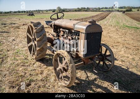 Vecchio e antico fordson tractorr lavorando con un aratro nei campi, mostrando come l'agricoltura è stata fatta molti anni fa. Foto Stock