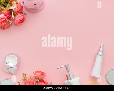Sfondo di bellezza con prodotti cosmetici per il corpo, fiori di rose su sfondo desktop color rosa chiaro pastello con spazio copia. Moderna struttura per la cura della pelle primaverile, Foto Stock