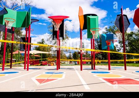 Los Angeles, California/USA - nastro giallo di attenzione, parco giochi per bambini e reti da basket dietro. Il parco giochi per bambini chiude la quarantena COVID-19 in CA. Foto Stock