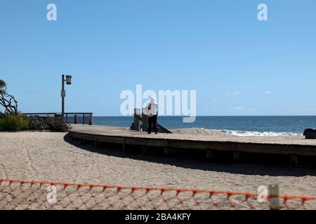 Laguna Beach, CA/USA - 23 marzo 2020: Un bagnino cammina sulla spiaggia recintata di Laguna Beach per far rispettare la chiusura COVID-19 Foto Stock