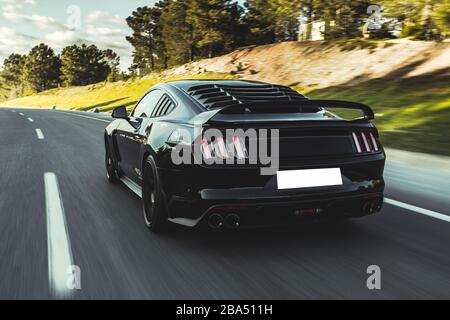 Auto sportiva nera con finestre in vinile nero sulla strada, vista posteriore Foto Stock