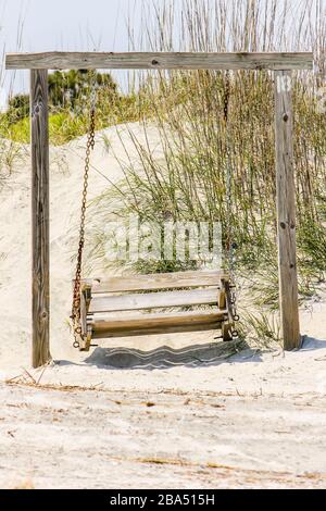 L'altalena vuota si trova alla base delle dune di sabbia di Tybee Island Beach. Un luogo tranquillo e rilassante con vista sull'Oceano Atlantico. Vicino a Savannah, Georgia. Foto Stock