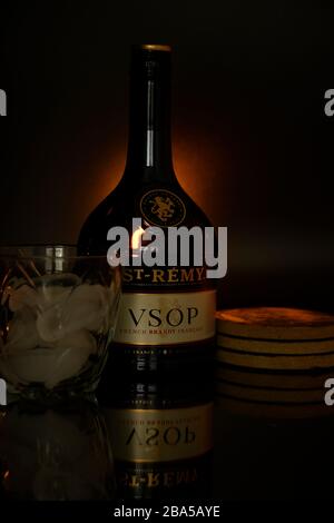 Studio con bottiglia da 750 ml di Brandy francese ST Remy VSOP con classe con ghiaccio, montagne russe, sfondo nero, retroilluminazione calda Foto Stock