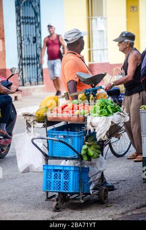 Scena della vita quotidiana nelle strade di Trinidad. Un venditore di verdure e frutta di strada attende i compratori per venire Foto Stock