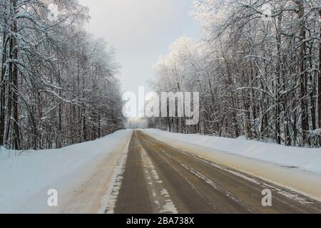 Inverno strada innevata attraverso la foresta Foto Stock