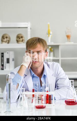 Un giovane scienziato brasiliano è stanco dopo aver completato la sua ricerca. Ambiente di lavoro in laboratorio chimico. Ha inventato un vaccino per prevenire Coronavir Foto Stock