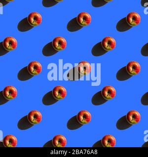 Modello di mele senza cuciture. Cibo creativo su sfondo blu. Frutta fresca di stagione con ombre forti Foto Stock