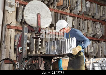 Un uomo come lavoratore è alla ricerca di uno stampo adatto nel magazzino di una fonderia Foto Stock