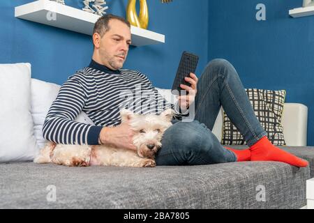 un uomo si rilassa con il suo cane sul divano Foto Stock
