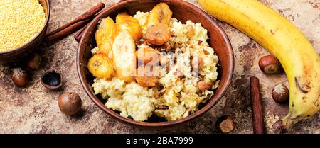 Porridge di miglio dolce con banane e noci in ciotola di ceramica. Foto Stock