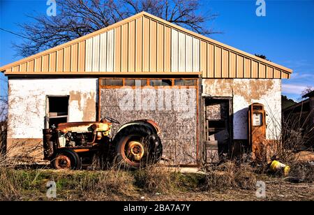 Vecchio trattore e pompa arrugginita di fronte a una vecchia casa Foto Stock