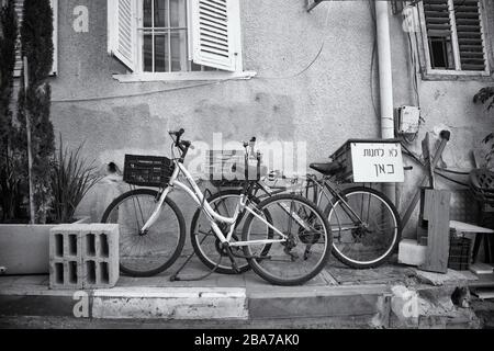 Foto in scala di grigi di due biciclette parcheggiate vicino all'edificio di Tel, Aviv, Israele Foto Stock