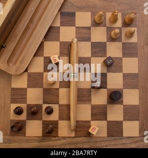 Una foto stilistica di una penna stilografica in legno posata su un set di scacchi Foto Stock