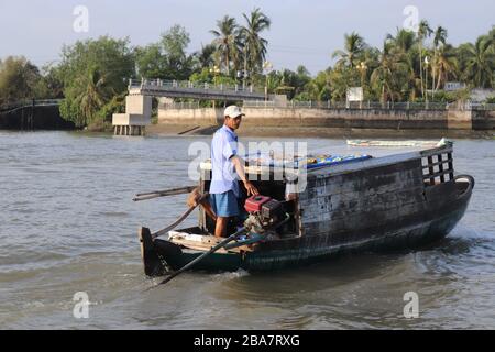 PERSONE VIETNAMITE CHE TRASPORTANO E COMMERCIANO MERCI SUL FIUME MEKONG NEL DELTA, VIETNAM. Foto Stock