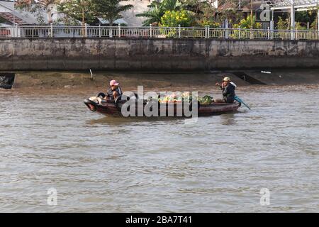 PERSONE VIETNAMITE CHE TRASPORTANO E COMMERCIANO MERCI SUL FIUME MEKONG NEL DELTA, VIETNAM. Foto Stock