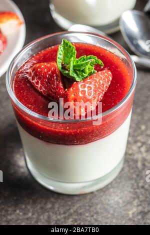 Panna cotta dolce italiano con fragole sul tavolo da cucina nero. Foto Stock