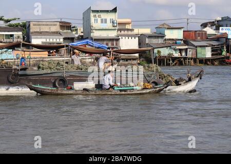 PERSONE VIETNAMITE CHE TRASPORTANO E COMMERCIANO MERCI SUL FIUME MEKONG NEL DELTA, VIETNAM. Foto Stock