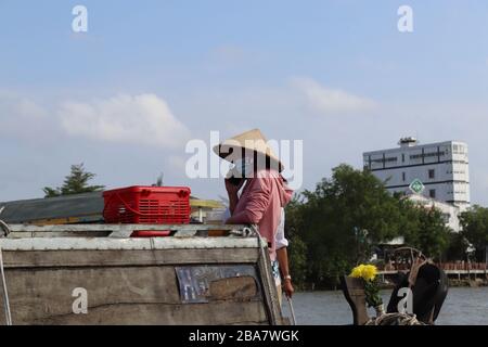 PERSONE VIETNAMITE CHE TRASPORTANO E COMMERCIANO MERCI SUL FIUME MEKONG NEL DELTA, VIETNAM. Foto Stock